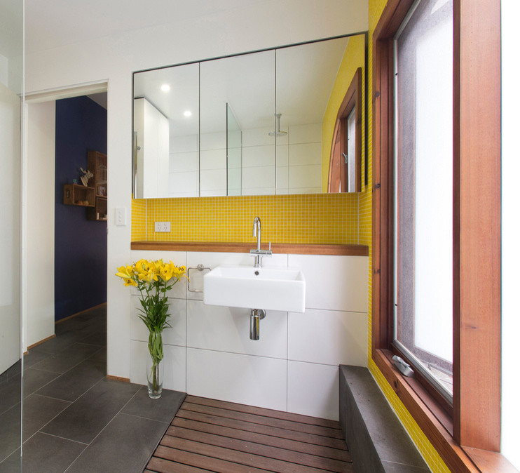 Bild på ett funkis badrum, med ett väggmonterat handfat och gul kakel