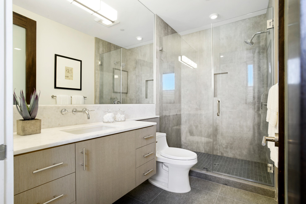 Idées déco pour une salle d'eau contemporaine en bois clair de taille moyenne avec un placard à porte plane, une douche ouverte, WC à poser, un carrelage gris, des carreaux de céramique, un mur blanc, un sol en carrelage de céramique, un lavabo encastré, un plan de toilette en marbre, un sol gris, une cabine de douche à porte battante, un plan de toilette blanc, meuble simple vasque et meuble-lavabo suspendu.