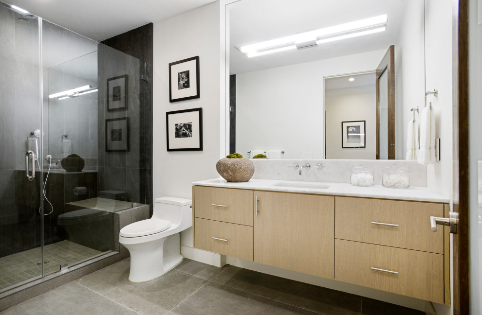 Inspiration pour une salle d'eau design en bois clair de taille moyenne avec un placard à porte plane, une douche ouverte, WC à poser, un carrelage gris, des carreaux de céramique, un mur noir, un sol en carrelage de céramique, un lavabo encastré, un plan de toilette en marbre, un sol gris, une cabine de douche à porte battante, un plan de toilette blanc, un banc de douche, meuble simple vasque et meuble-lavabo suspendu.