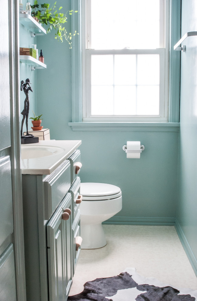 Esempio di una piccola stanza da bagno padronale minimal con ante con bugna sagomata, ante blu, vasca da incasso, vasca/doccia, WC a due pezzi, piastrelle bianche, pareti blu, pavimento in vinile, lavabo integrato e top in superficie solida