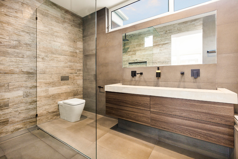Modern inredning av ett badrum, med luckor med infälld panel, en toalettstol med hel cisternkåpa, grå kakel, kalkstensgolv, bänkskiva i betong, grått golv och med dusch som är öppen