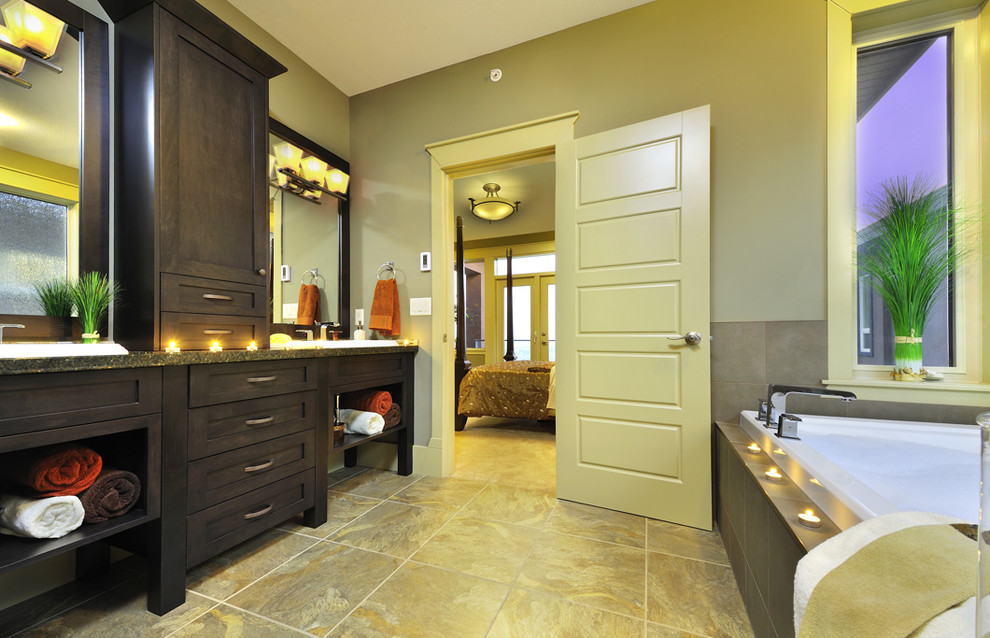 На фото: ванная комната: освещение в современном стиле с накладной раковиной, фасадами в стиле шейкер, темными деревянными фасадами, гидромассажной ванной и бежевой плиткой с
