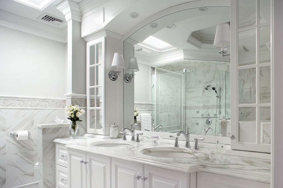 Example of a large classic master gray tile, white tile and marble tile marble floor and multicolored floor alcove shower design in New York with raised-panel cabinets, white cabinets, a one-piece toilet, multicolored walls, an undermount sink, marble countertops and a hinged shower door