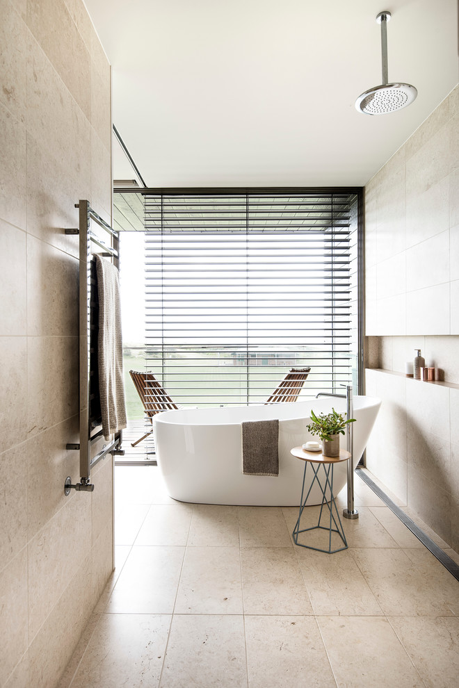 Aménagement d'une salle de bain principale contemporaine en bois clair avec une baignoire indépendante, un carrelage beige, un carrelage de pierre, un mur beige, un sol en marbre, un lavabo encastré et un plan de toilette en quartz modifié.