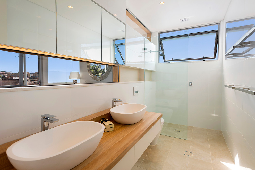 Diseño de cuarto de baño largo y estrecho contemporáneo de tamaño medio con lavabo sobreencimera, encimera de madera, ducha abierta, baldosas y/o azulejos beige, paredes blancas y ducha abierta