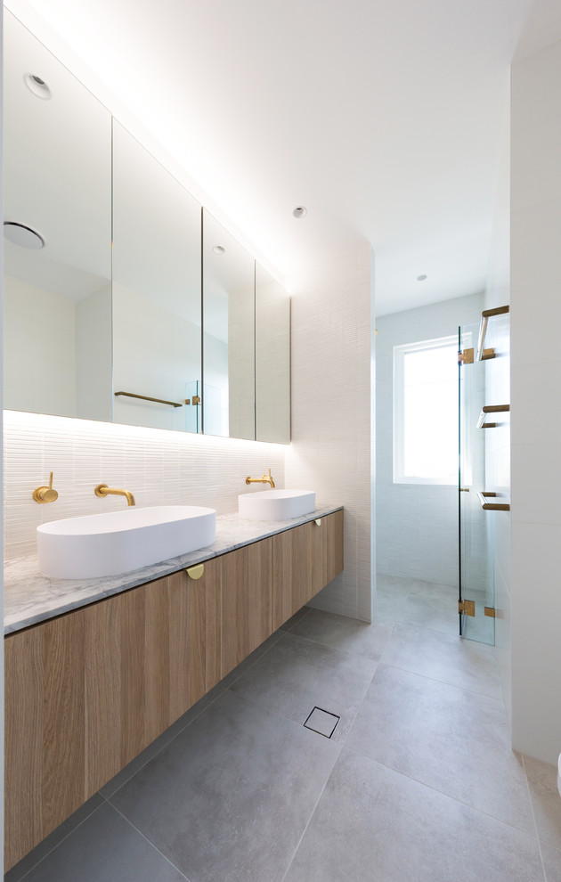 Design ideas for a contemporary bathroom in Sydney with flat-panel cabinets, medium wood cabinets, white tiles, a vessel sink, grey floors and white worktops.