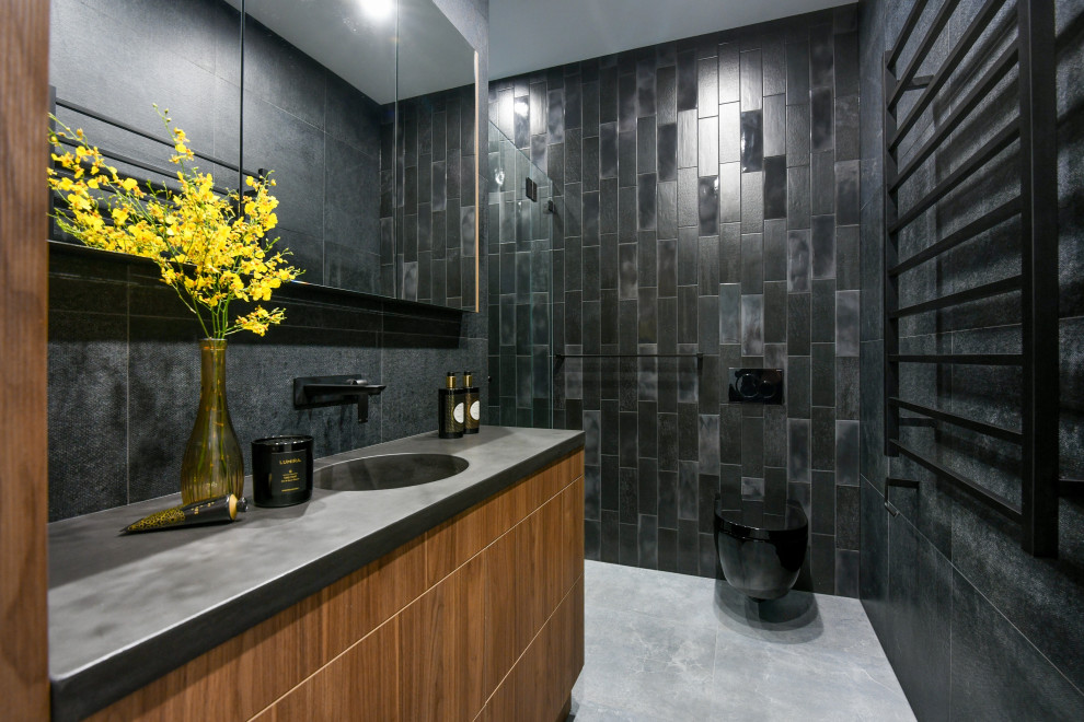 Modernes Badezimmer mit flächenbündigen Schrankfronten, hellbraunen Holzschränken, Wandtoilette, schwarzen Fliesen, integriertem Waschbecken, grauem Boden und grauer Waschtischplatte in Sydney
