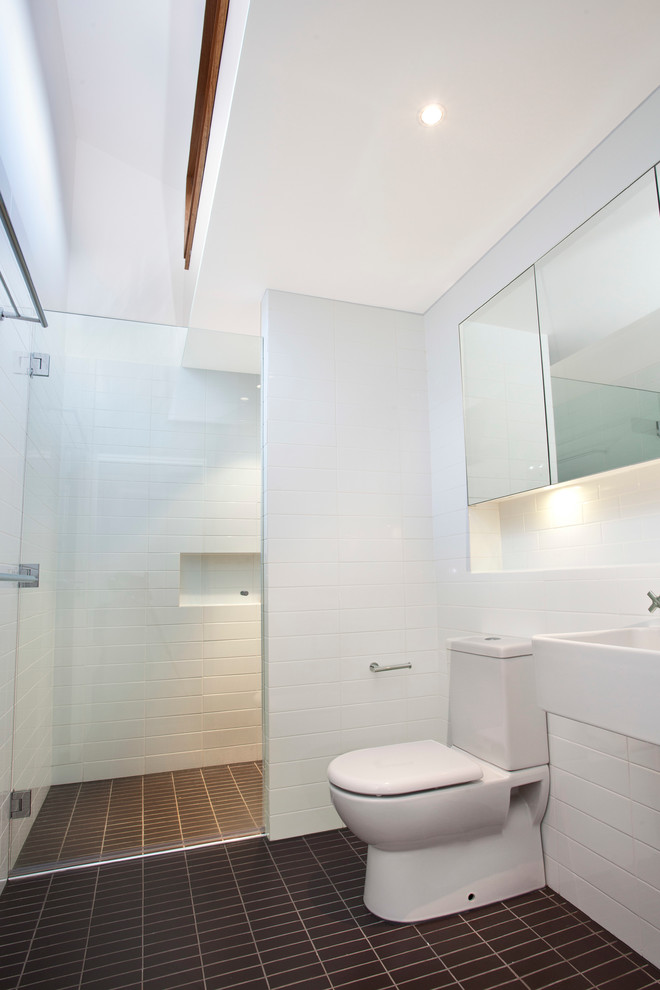 На фото: ванная комната в стиле модернизм с подвесной раковиной и коричневым полом с