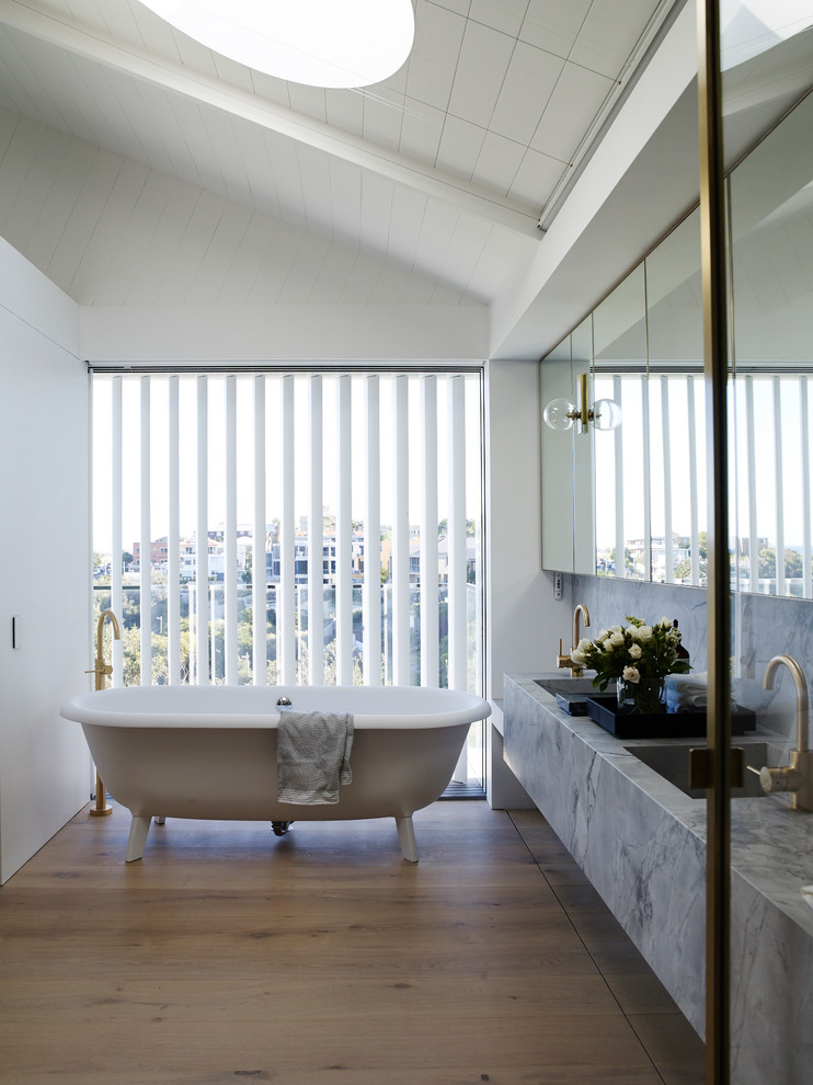 Modernes Badezimmer mit freistehender Badewanne, weißer Wandfarbe, hellem Holzboden, integriertem Waschbecken und beigem Boden in Sydney