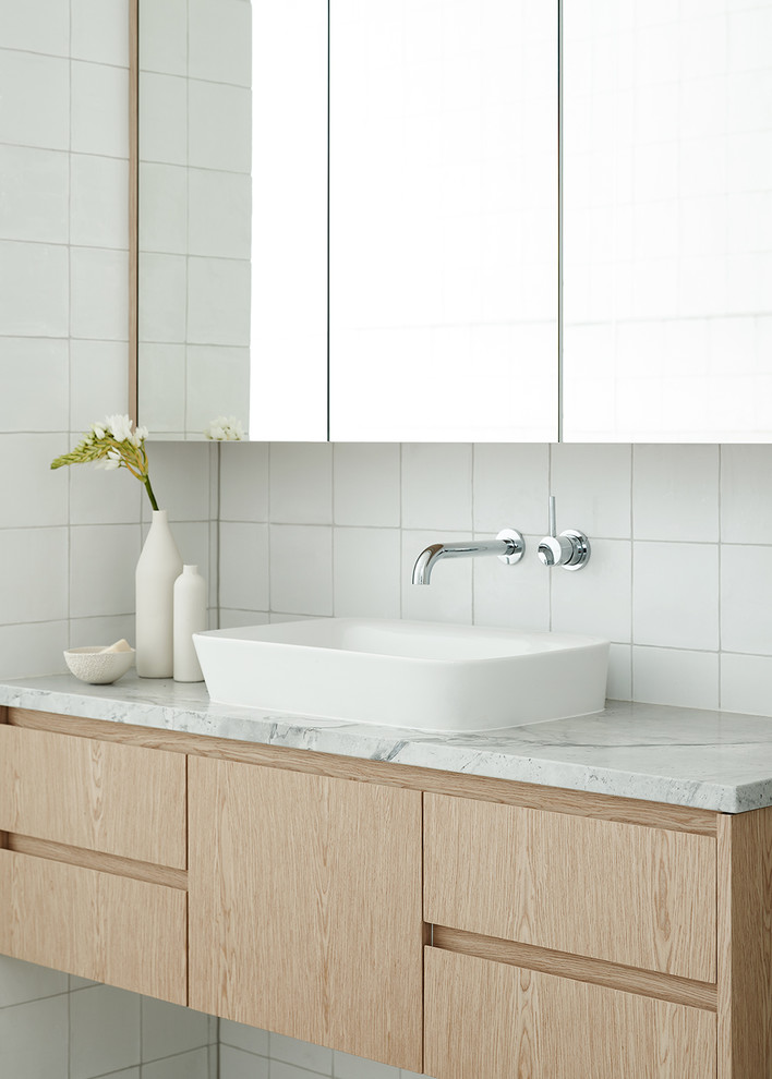 Стильный дизайн: ванная комната в современном стиле с плоскими фасадами, светлыми деревянными фасадами, белой плиткой, белыми стенами, настольной раковиной и белой столешницей - последний тренд