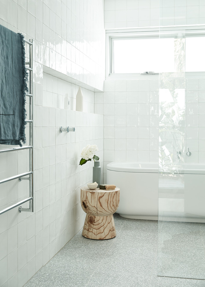 Esempio di una stanza da bagno minimal con vasca freestanding, doccia a filo pavimento, piastrelle bianche, pareti bianche, pavimento alla veneziana, pavimento grigio e doccia aperta
