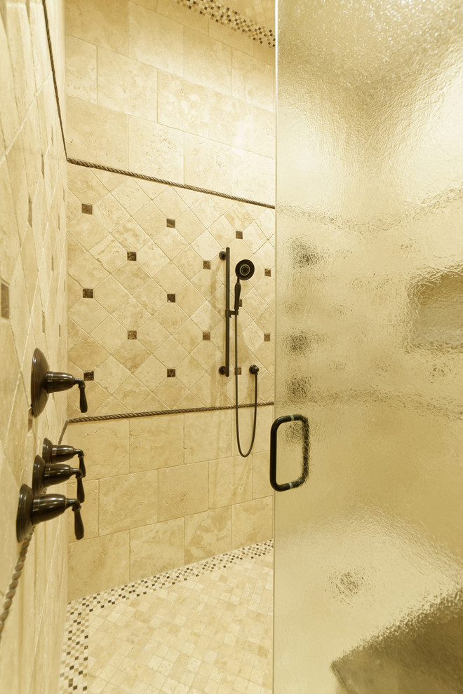 На фото: главная ванная комната в средиземноморском стиле с фасадами с выступающей филенкой, темными деревянными фасадами, накладной ванной, бежевой плиткой, каменной плиткой, бежевыми стенами, полом из травертина, врезной раковиной и мраморной столешницей