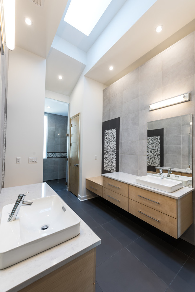 他の地域にあるコンテンポラリースタイルのおしゃれな浴室 (ベッセル式洗面器、フラットパネル扉のキャビネット、淡色木目調キャビネット、グレーのタイル、白い壁) の写真