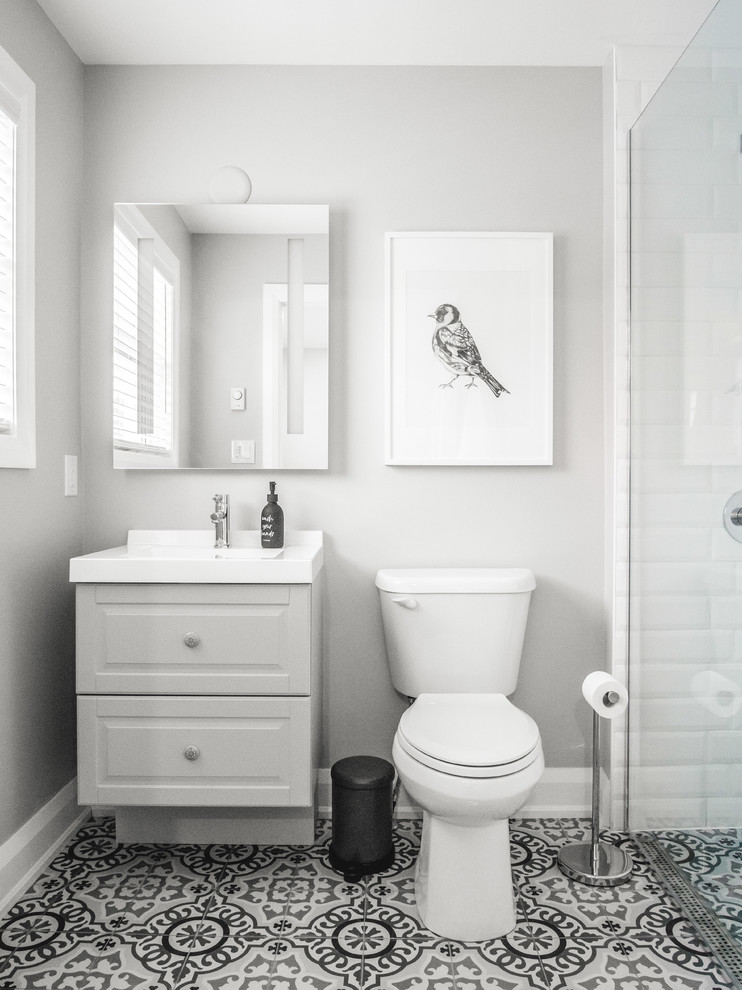 Modelo de cuarto de baño tradicional renovado con armarios con paneles con relieve, puertas de armario grises, sanitario de dos piezas, baldosas y/o azulejos blancos, paredes grises, aseo y ducha y encimeras blancas