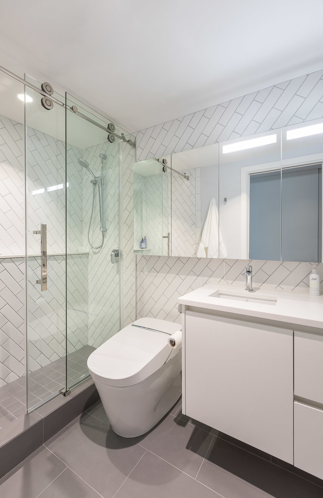 Bathroom - small contemporary white tile and ceramic tile porcelain tile bathroom idea in Vancouver with flat-panel cabinets, white cabinets, a one-piece toilet, white walls, an undermount sink, quartz countertops and white countertops