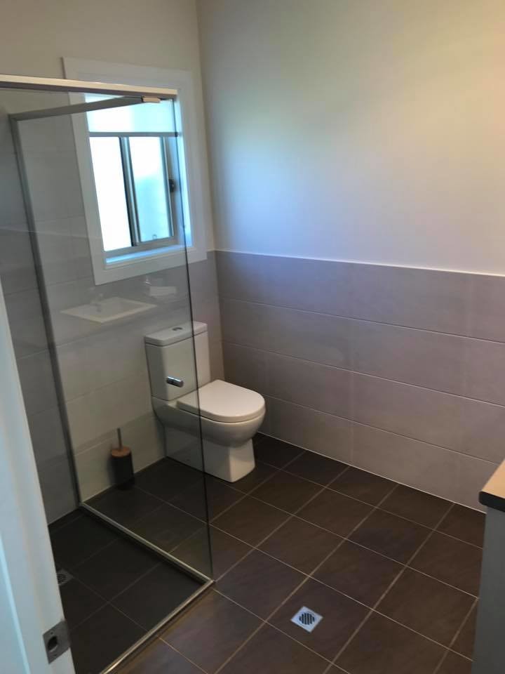 Inspiration for a modern shower room bathroom in Adelaide with a corner shower, a one-piece toilet, grey tiles, porcelain tiles, grey walls, porcelain flooring, brown floors and a hinged door.