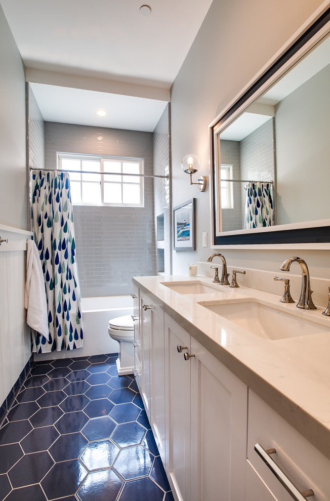 На фото: детская ванная комната в морском стиле с фасадами в стиле шейкер, белыми фасадами, ванной в нише, душем над ванной, унитазом-моноблоком, серой плиткой, керамической плиткой, серыми стенами, полом из керамической плитки, врезной раковиной, столешницей из искусственного кварца, синим полом, шторкой для ванной и белой столешницей с
