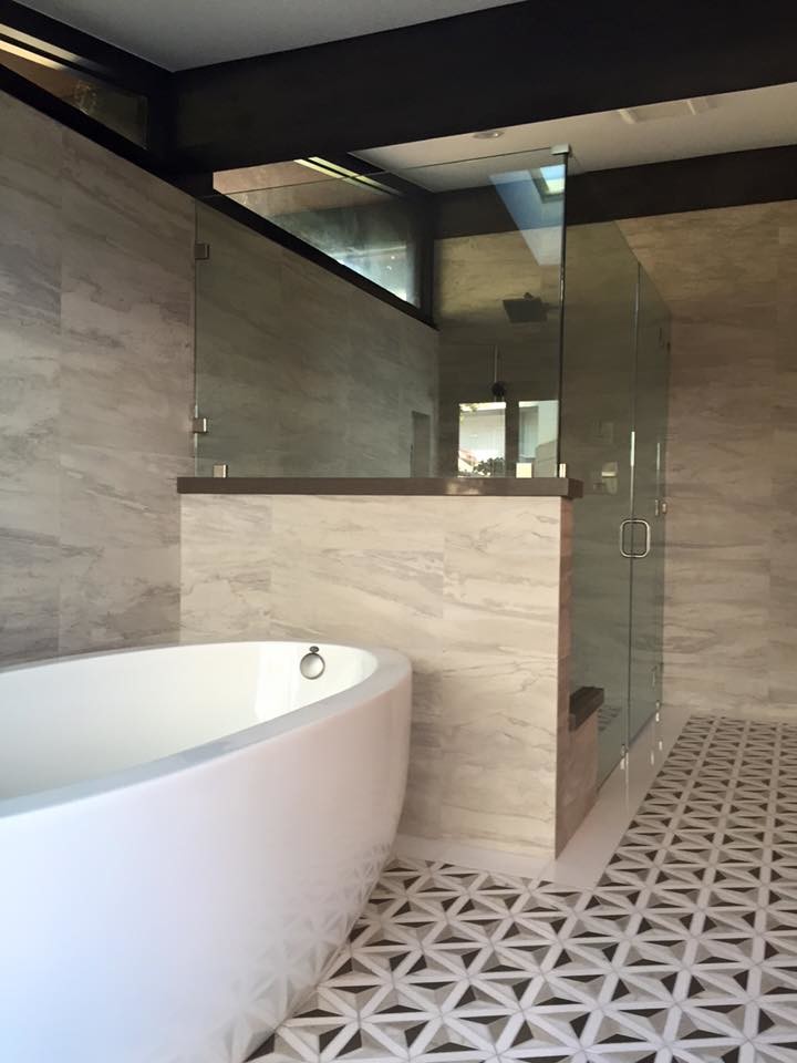 Large transitional master beige tile and porcelain tile multicolored floor bathroom photo in Los Angeles with flat-panel cabinets, black cabinets, beige walls, a vessel sink, solid surface countertops and a hinged shower door