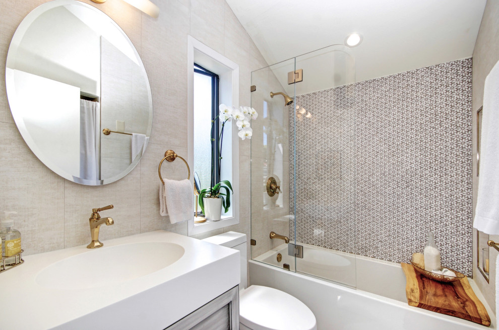 На фото: ванная комната в стиле неоклассика (современная классика) с фасадами с утопленной филенкой, серыми фасадами, ванной в нише, душем над ванной, серой плиткой, монолитной раковиной, открытым душем и белой столешницей