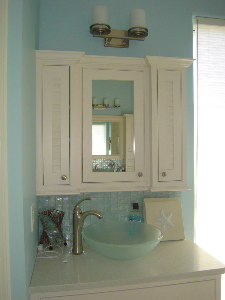 На фото: большая главная ванная комната в морском стиле с настольной раковиной, фасадами с филенкой типа жалюзи, белыми фасадами, столешницей из кварцита, отдельно стоящей ванной, открытым душем, синей плиткой, стеклянной плиткой, синими стенами и полом из керамогранита