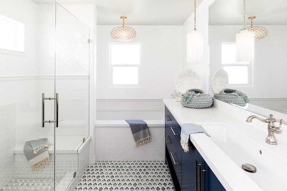 Klassisches Badezimmer mit flächenbündigen Schrankfronten, blauen Schränken, Unterbauwanne, Duschnische, weißen Fliesen, weißer Wandfarbe, Unterbauwaschbecken, buntem Boden, Falttür-Duschabtrennung und weißer Waschtischplatte in San Diego
