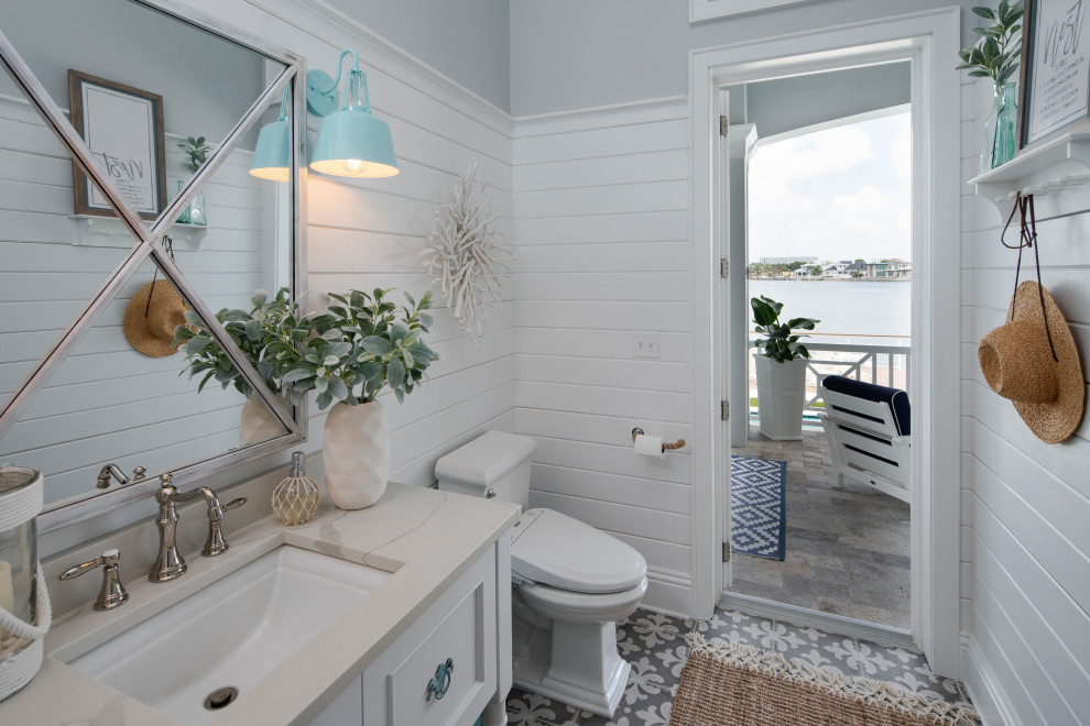 Maritimes Badezimmer mit Schrankfronten mit vertiefter Füllung, weißen Schränken, grauer Wandfarbe, Unterbauwaschbecken, grauem Boden, beiger Waschtischplatte, Einzelwaschbecken, freistehendem Waschtisch, Holzdielenwänden und vertäfelten Wänden in Tampa