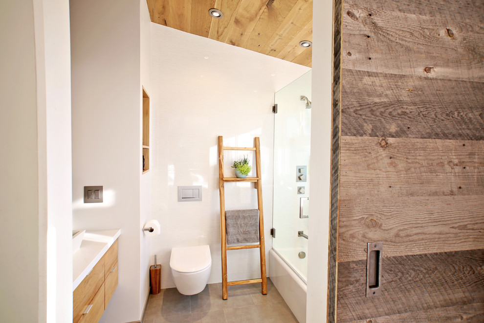 Идея дизайна: маленькая ванная комната в морском стиле с плоскими фасадами, светлыми деревянными фасадами, накладной ванной, душем в нише, инсталляцией, белой плиткой, керамогранитной плиткой, белыми стенами, полом из керамогранита, душевой кабиной, настольной раковиной, столешницей из искусственного кварца, серым полом, душем с раздвижными дверями и белой столешницей для на участке и в саду