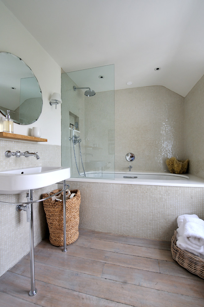 Immagine di una stanza da bagno costiera con vasca sottopiano, vasca/doccia, piastrelle beige, pavimento in legno massello medio e lavabo a consolle