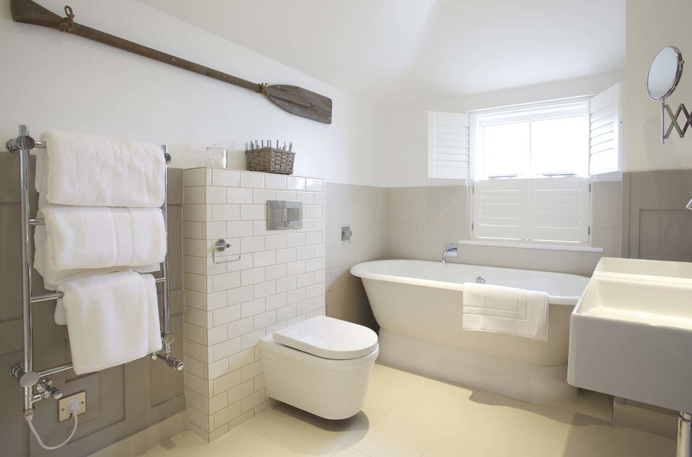Modelo de cuarto de baño principal marinero con bañera exenta, sanitario de pared, baldosas y/o azulejos grises, baldosas y/o azulejos de cemento y paredes blancas