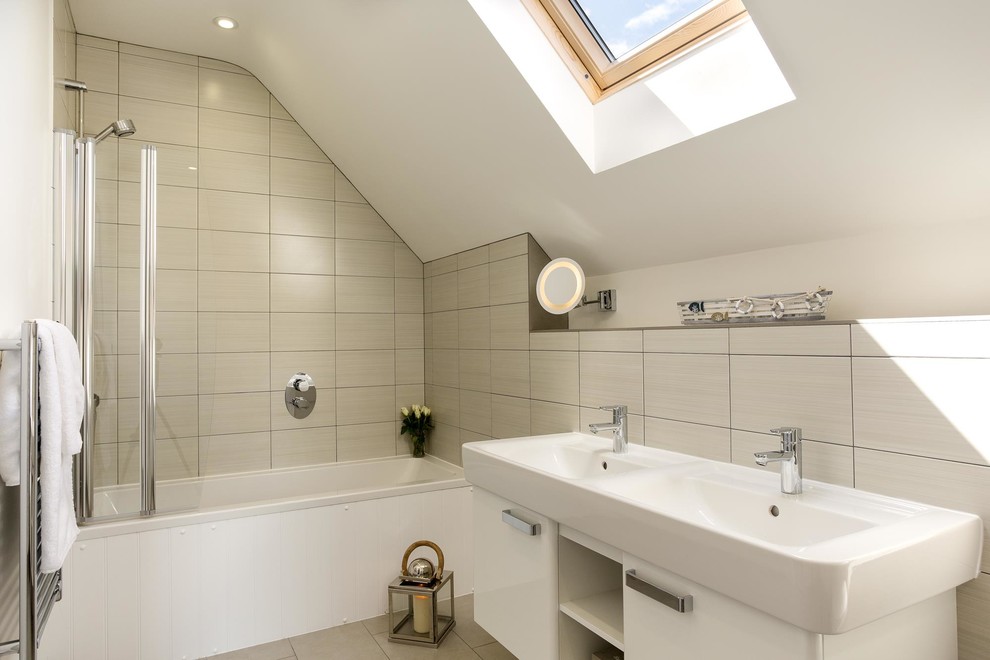 Maritimes Badezimmer En Suite mit flächenbündigen Schrankfronten, weißen Schränken, Einbaubadewanne, Duschbadewanne, beigen Fliesen und integriertem Waschbecken in Cornwall