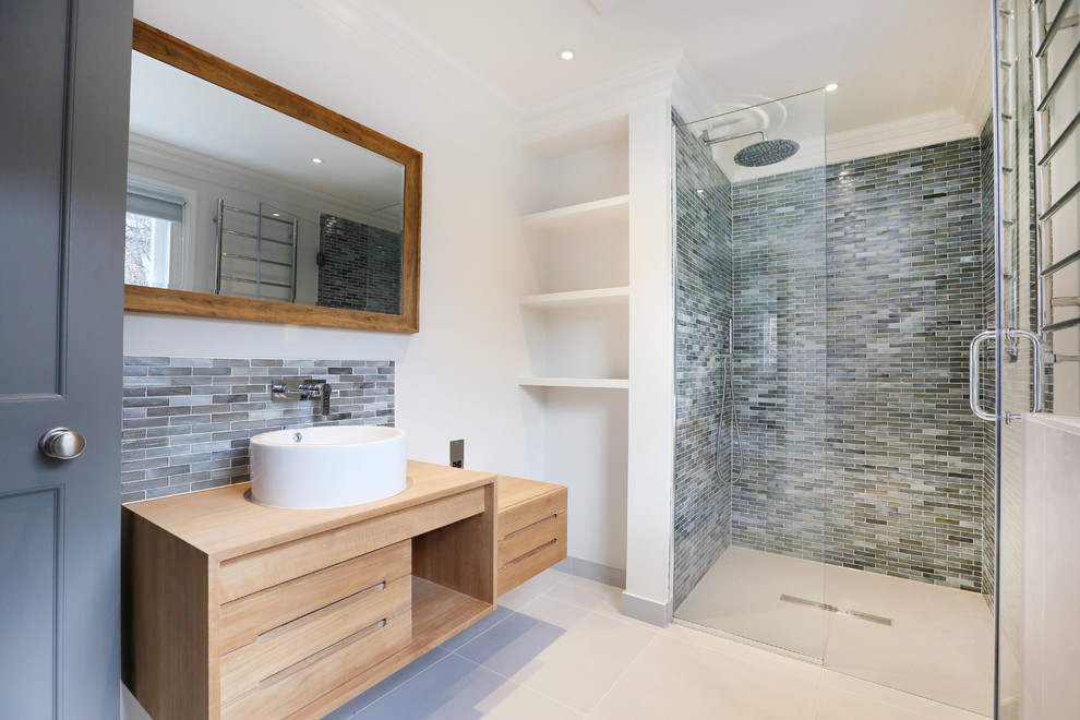 Cette image montre une salle de bain design en bois clair avec un placard à porte plane, des carreaux en allumettes, un mur blanc, une vasque, un plan de toilette en bois, un carrelage gris, une cabine de douche à porte battante et un plan de toilette beige.