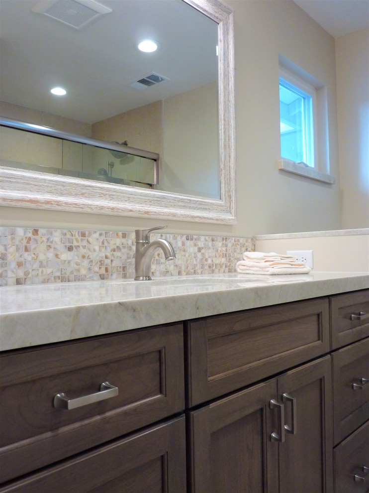 Photo of a small beach style ensuite bathroom in San Francisco with shaker cabinets, medium wood cabinets, an alcove shower, beige tiles, mosaic tiles, beige walls, limestone flooring, a submerged sink, quartz worktops and a sliding door.