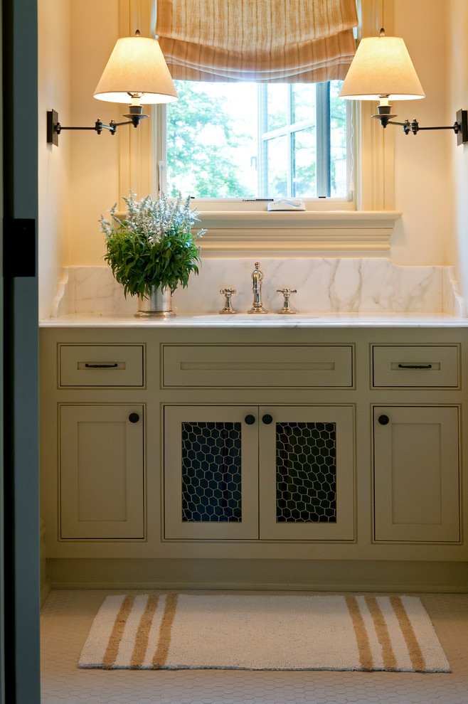 Immagine di una stanza da bagno costiera con ante in stile shaker, ante beige, top in marmo, top bianco, un lavabo e mobile bagno incassato
