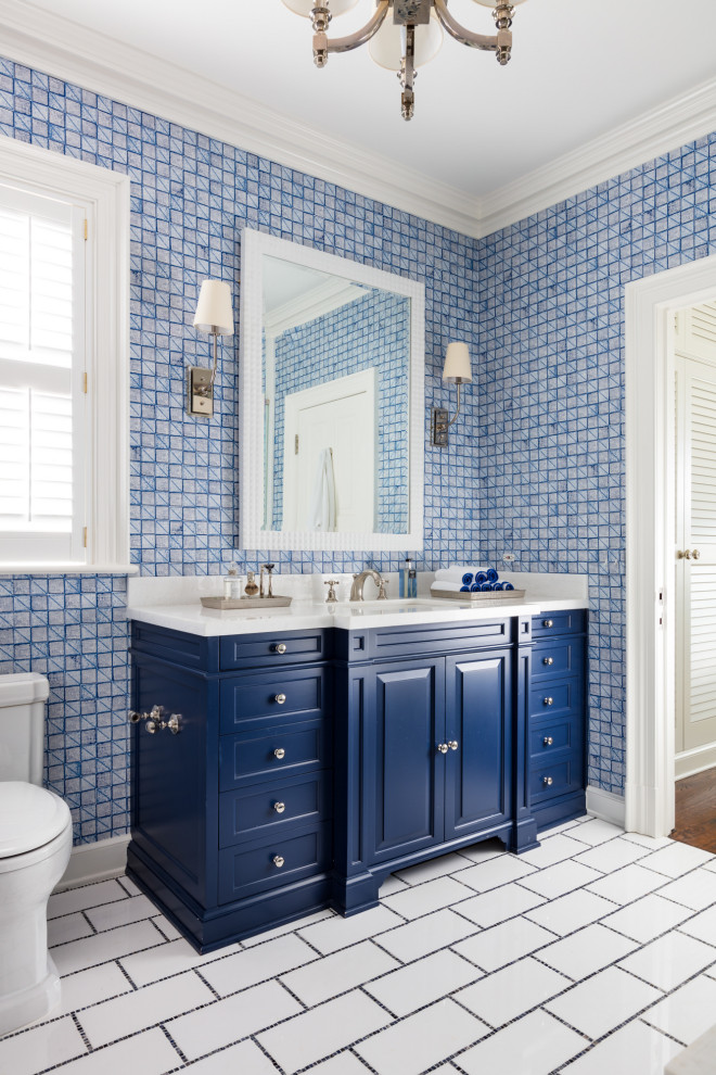 Foto di una stanza da bagno con doccia tropicale con ante con bugna sagomata, ante blu, WC a due pezzi, pareti blu, lavabo sottopiano, pavimento bianco e top bianco