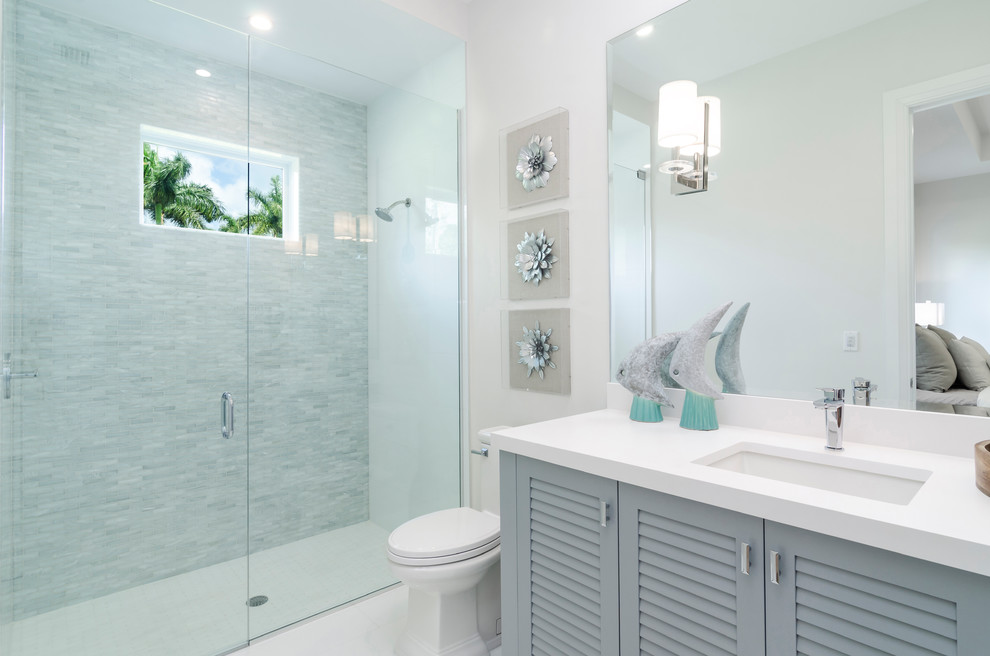 Mid-sized beach style master white tile ceramic tile and white floor double shower photo in Miami with shaker cabinets, blue cabinets, white walls, a drop-in sink, quartzite countertops, a hinged shower door and white countertops