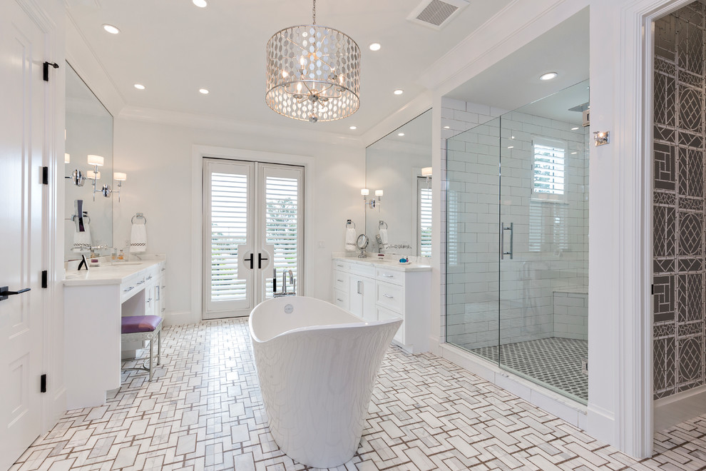 Пример оригинального дизайна: большая главная ванная комната в стиле неоклассика (современная классика) с белыми фасадами, отдельно стоящей ванной, белой плиткой, керамической плиткой, белыми стенами, полом из мозаичной плитки, врезной раковиной, мраморной столешницей, душем с распашными дверями и белой столешницей