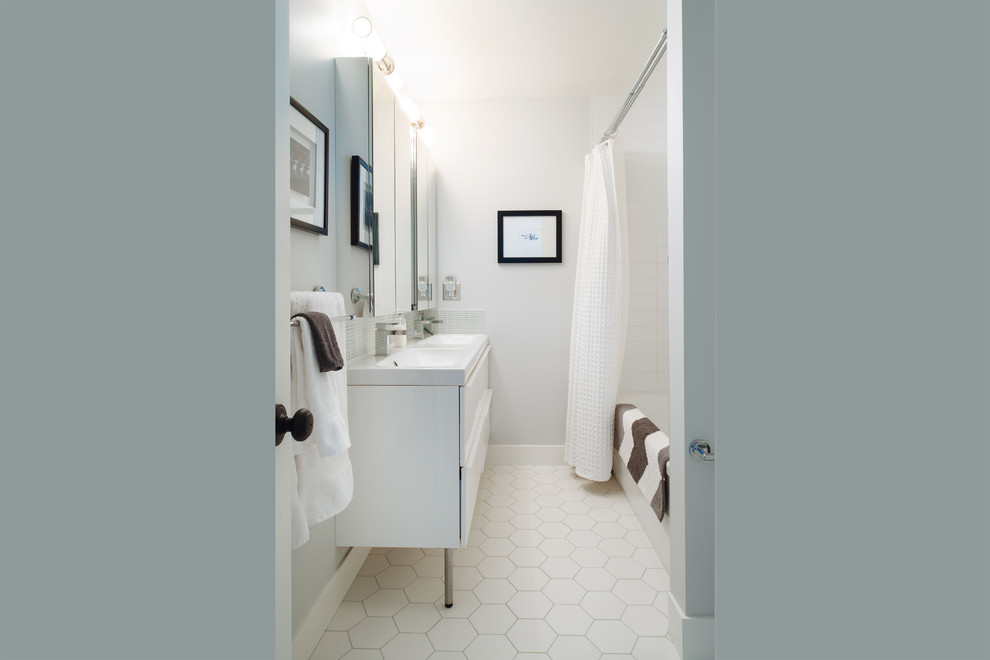 バンクーバーにある高級な中くらいなビーチスタイルのおしゃれな浴室 (フラットパネル扉のキャビネット、白いキャビネット、アルコーブ型浴槽、シャワー付き浴槽	、白い壁、一体型シンク) の写真