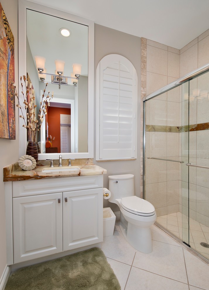 This is an example of a medium sized world-inspired shower room bathroom in Miami with raised-panel cabinets, white cabinets, a walk-in shower, a one-piece toilet, beige tiles, porcelain tiles, beige walls, porcelain flooring, a submerged sink and onyx worktops.