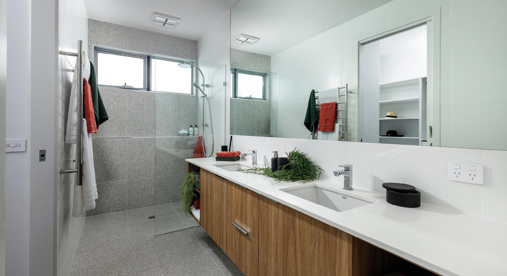 Foto på ett funkis vit badrum, med släta luckor, skåp i mellenmörkt trä, en dusch i en alkov, grå kakel, ett undermonterad handfat, grått golv och med dusch som är öppen