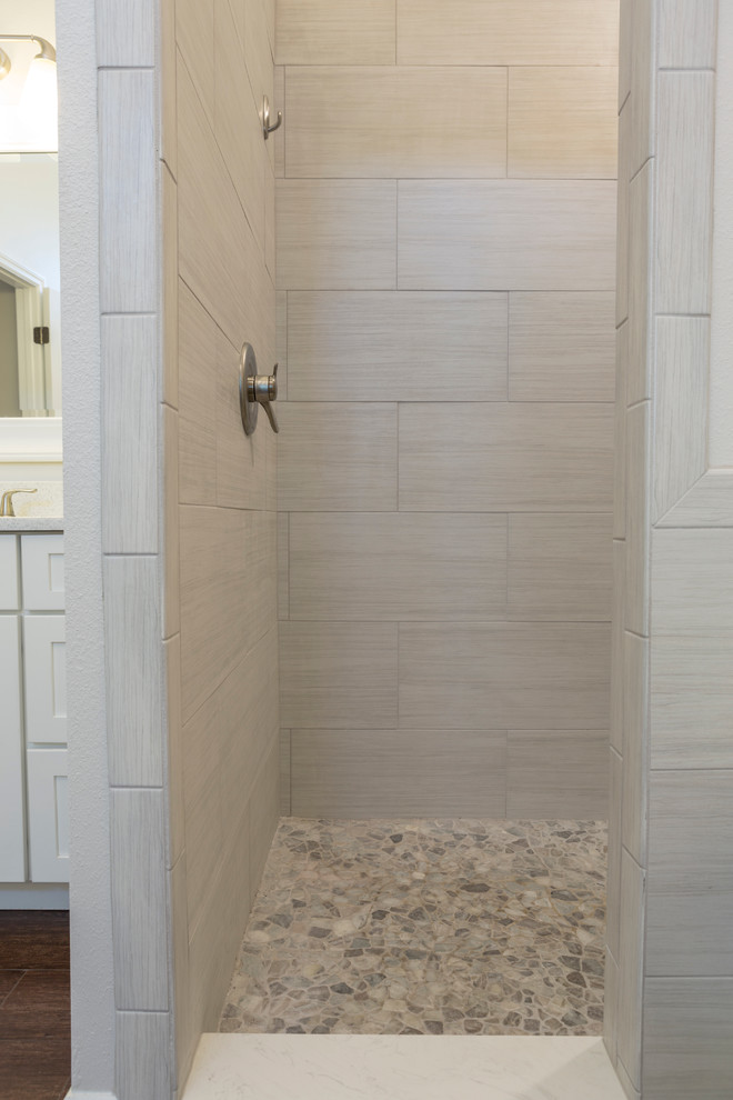 Example of a mid-sized transitional master brown tile and porcelain tile pebble tile floor bathroom design in Tampa with shaker cabinets, white cabinets, quartz countertops, an undermount sink, a one-piece toilet and gray walls