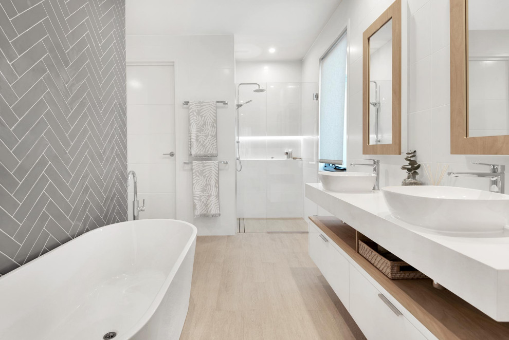 Foto på ett stort funkis vit en-suite badrum, med öppna hyllor, vita skåp, ett fristående badkar, en dusch i en alkov, grå kakel, porslinskakel, vita väggar, ett fristående handfat, beiget golv och dusch med gångjärnsdörr