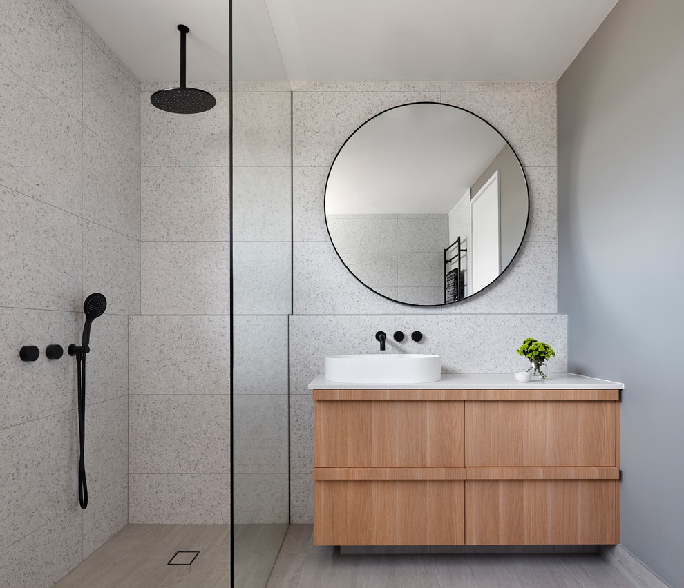 Photo of a medium sized beach style ensuite bathroom in Melbourne with recessed-panel cabinets, light wood cabinets, a freestanding bath, a walk-in shower, grey tiles, stone tiles, a vessel sink, concrete worktops, grey floors, a hinged door and white worktops.