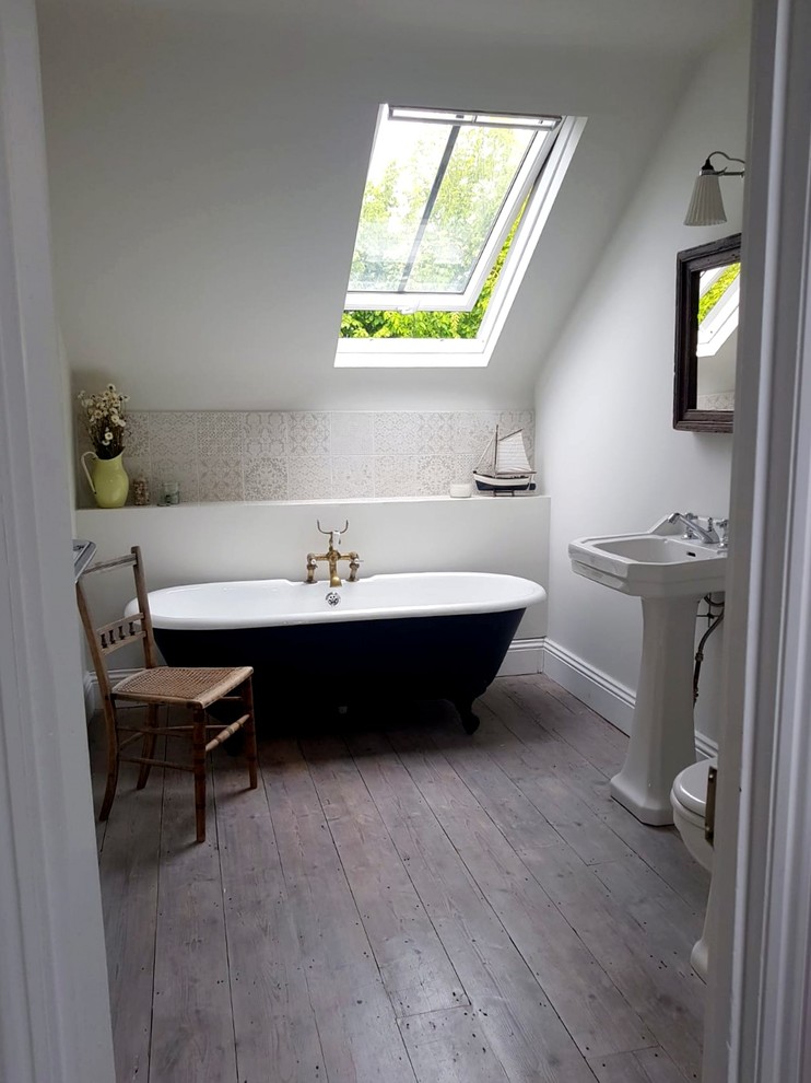 Kleines Maritimes Badezimmer En Suite mit Löwenfuß-Badewanne, Wandtoilette mit Spülkasten, Porzellanfliesen, grauer Wandfarbe, braunem Holzboden, Sockelwaschbecken und weißem Boden in Sussex
