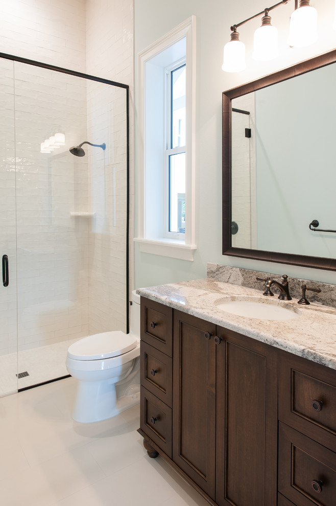 Example of a mid-sized transitional master white tile and matchstick tile ceramic tile and beige floor bathroom design in Orlando with recessed-panel cabinets, dark wood cabinets, a one-piece toilet, blue walls, an undermount sink and a hinged shower door