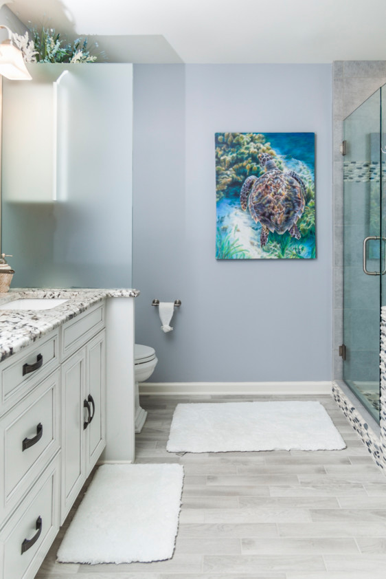 Ejemplo de cuarto de baño principal marinero pequeño con armarios con paneles empotrados, bañera encastrada, paredes azules, suelo de baldosas de porcelana, lavabo bajoencimera, encimera de granito y suelo gris