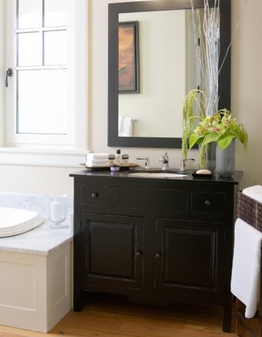 Example of a mid-sized beach style master light wood floor drop-in bathtub design in Atlanta with an undermount sink, raised-panel cabinets, black cabinets, quartz countertops and white walls