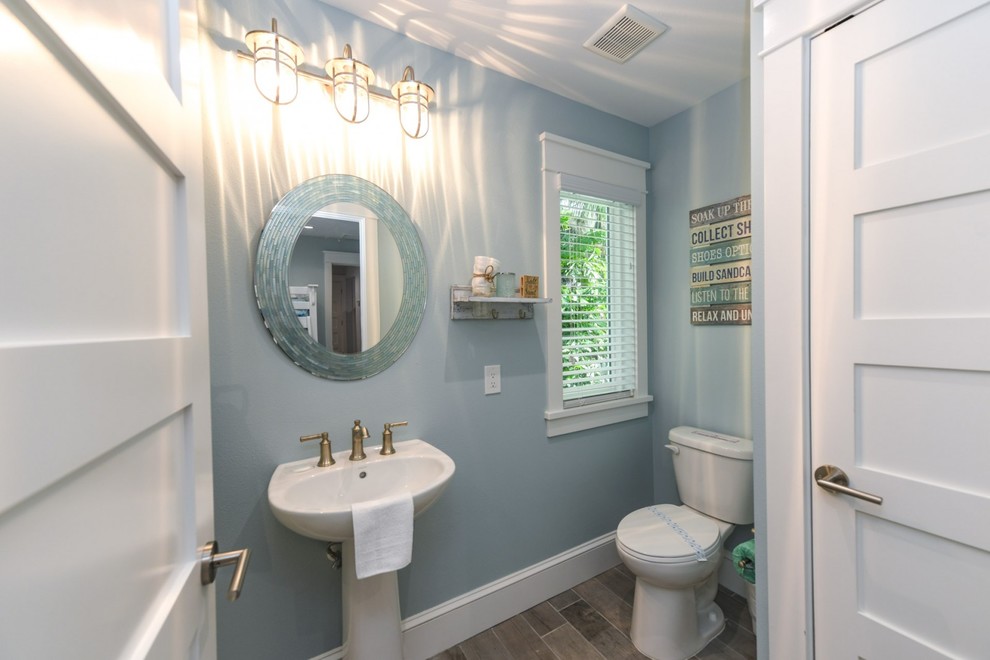 На фото: ванная комната в морском стиле с унитазом-моноблоком, синими стенами, полом из фанеры, раковиной с пьедесталом и серым полом с