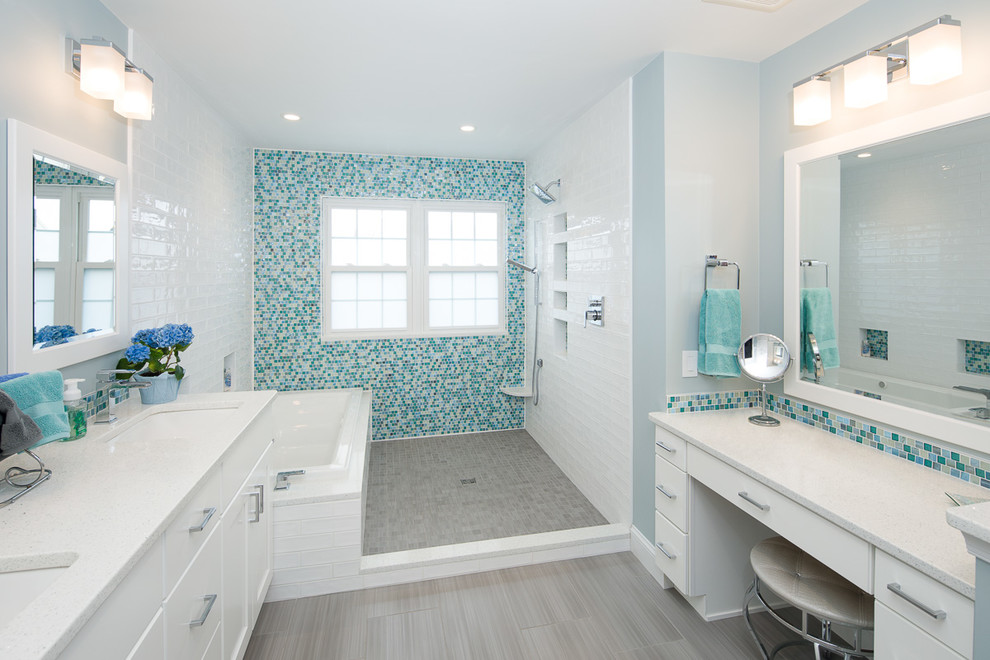 This is an example of a large coastal wet room bathroom in Philadelphia with flat-panel cabinets, white cabinets, a built-in bath, a bidet, blue tiles, mosaic tiles, blue walls, porcelain flooring, a submerged sink, engineered stone worktops, grey floors, an open shower and white worktops.