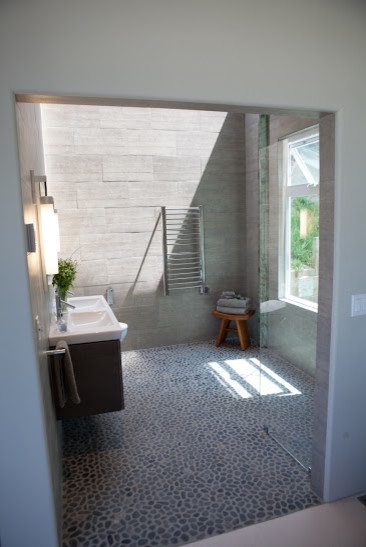 Пример оригинального дизайна: главная ванная комната среднего размера в стиле модернизм с серой плиткой, плоскими фасадами, серыми фасадами, душем без бортиков, биде, каменной плиткой, серыми стенами, полом из галечной плитки, монолитной раковиной, серым полом и открытым душем