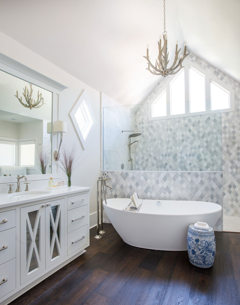 Exempel på ett klassiskt vit vitt en-suite badrum, med vita skåp, ett fristående badkar, en öppen dusch, en toalettstol med hel cisternkåpa, grå kakel, marmorkakel, vita väggar, mörkt trägolv, ett undermonterad handfat, bänkskiva i kvarts, brunt golv, med dusch som är öppen och släta luckor